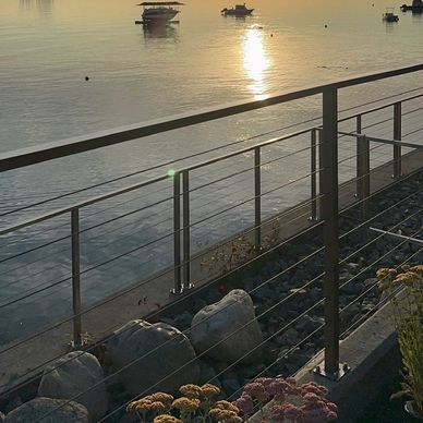 Sunset over a calm waterfront with boats and beautiful cable railing.