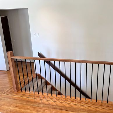 Wood and metal stair railing with black metal balusters.