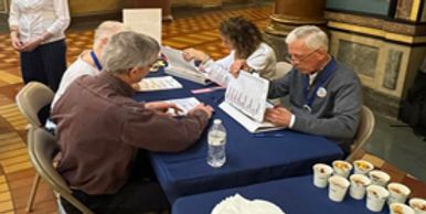 A team of four people demonstrating hand counting ballots.