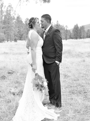 Bride and groom share a tender moment outdoors in black and white.