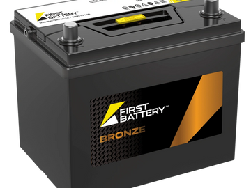 A black First Battery Bronze car battery with yellow and orange branding.