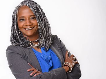 Confident woman with silver braids in business attire smiling.