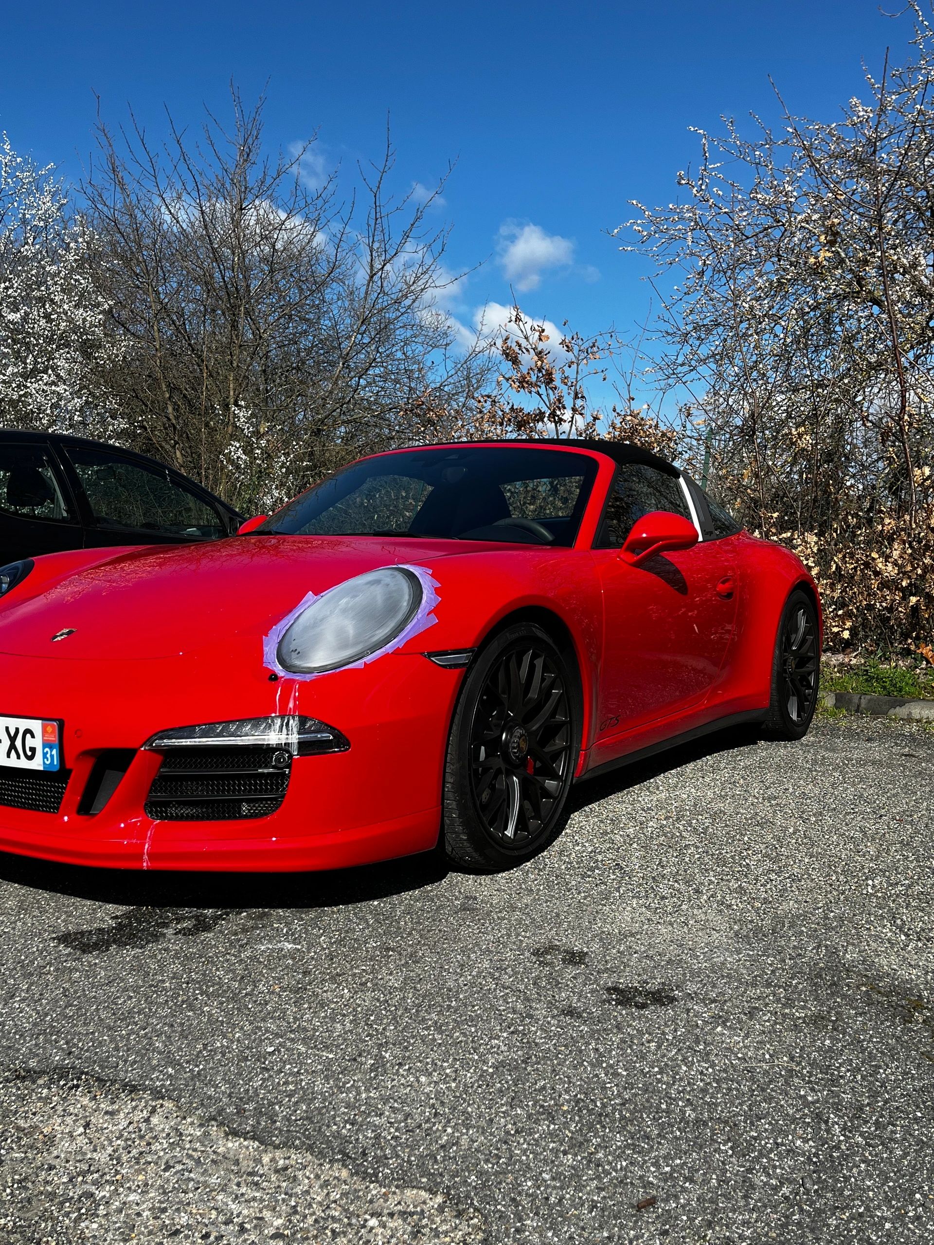 Porsche rouge pendant une intervention sur ses phares