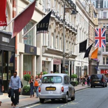 Busy London street with iconic black cabs and British flags.
