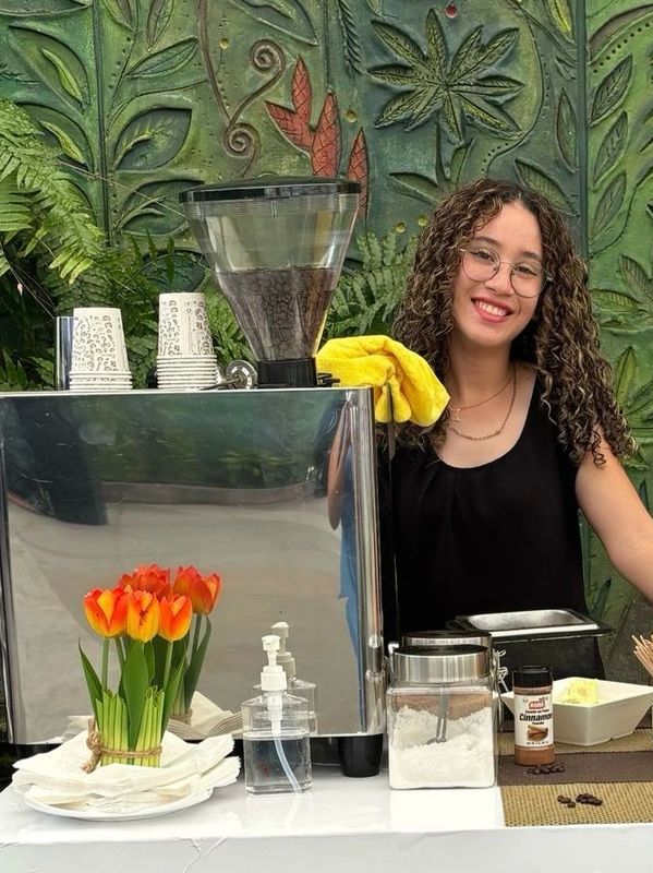 Smiling barista stands beside coffee machine 