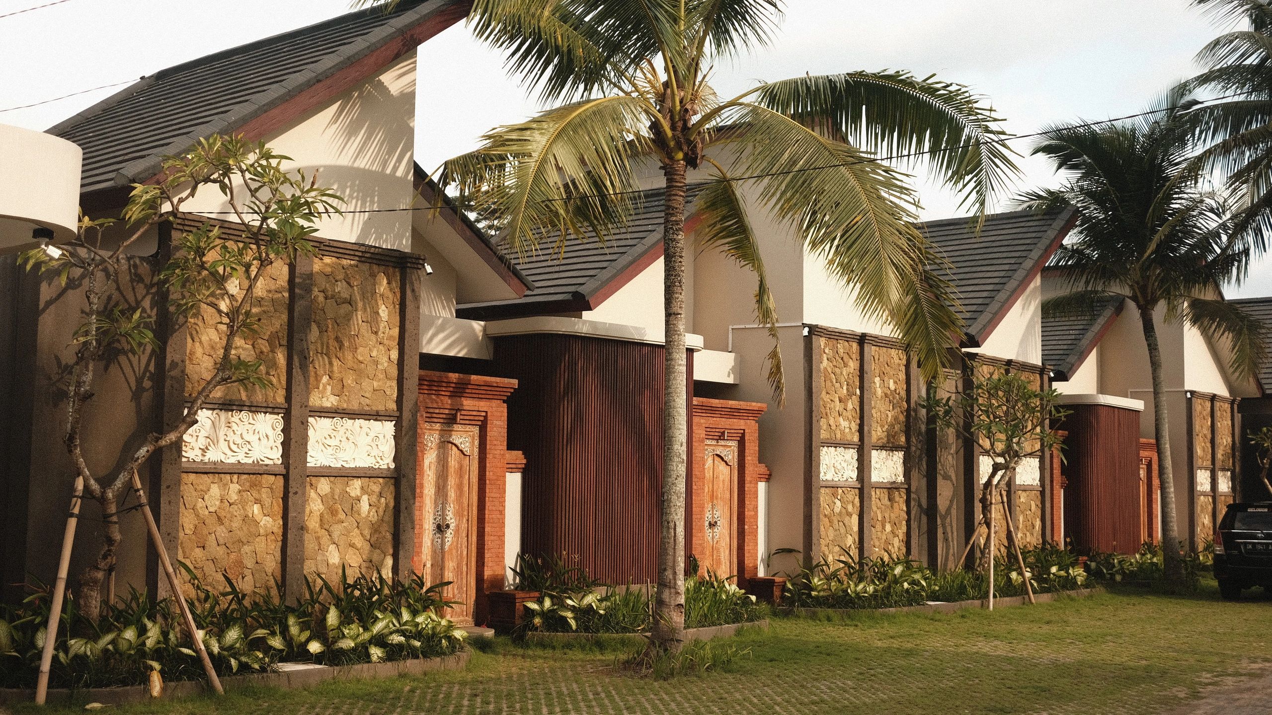 Modern houses with stone walls and tropical palm trees outside.