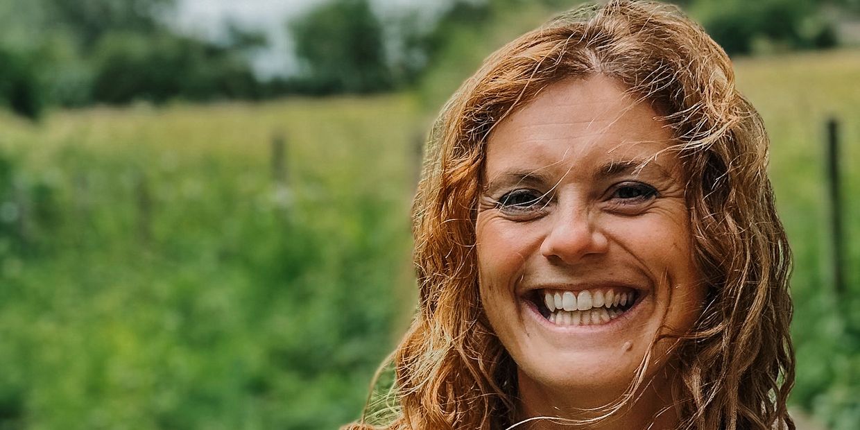 Smiling woman with curly hair outdoors.