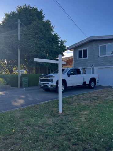 White pickup truck parked near a house with an empty white signpost.