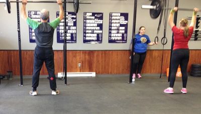 Three athletes working on overhead pressing with a barbell. 