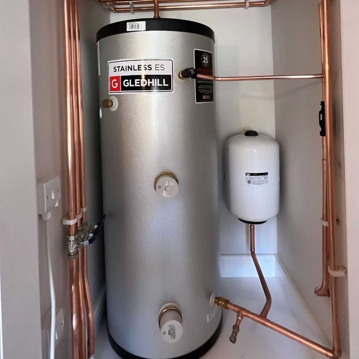 A neatly installed Gledhill stainless steel water heater with copper piping.