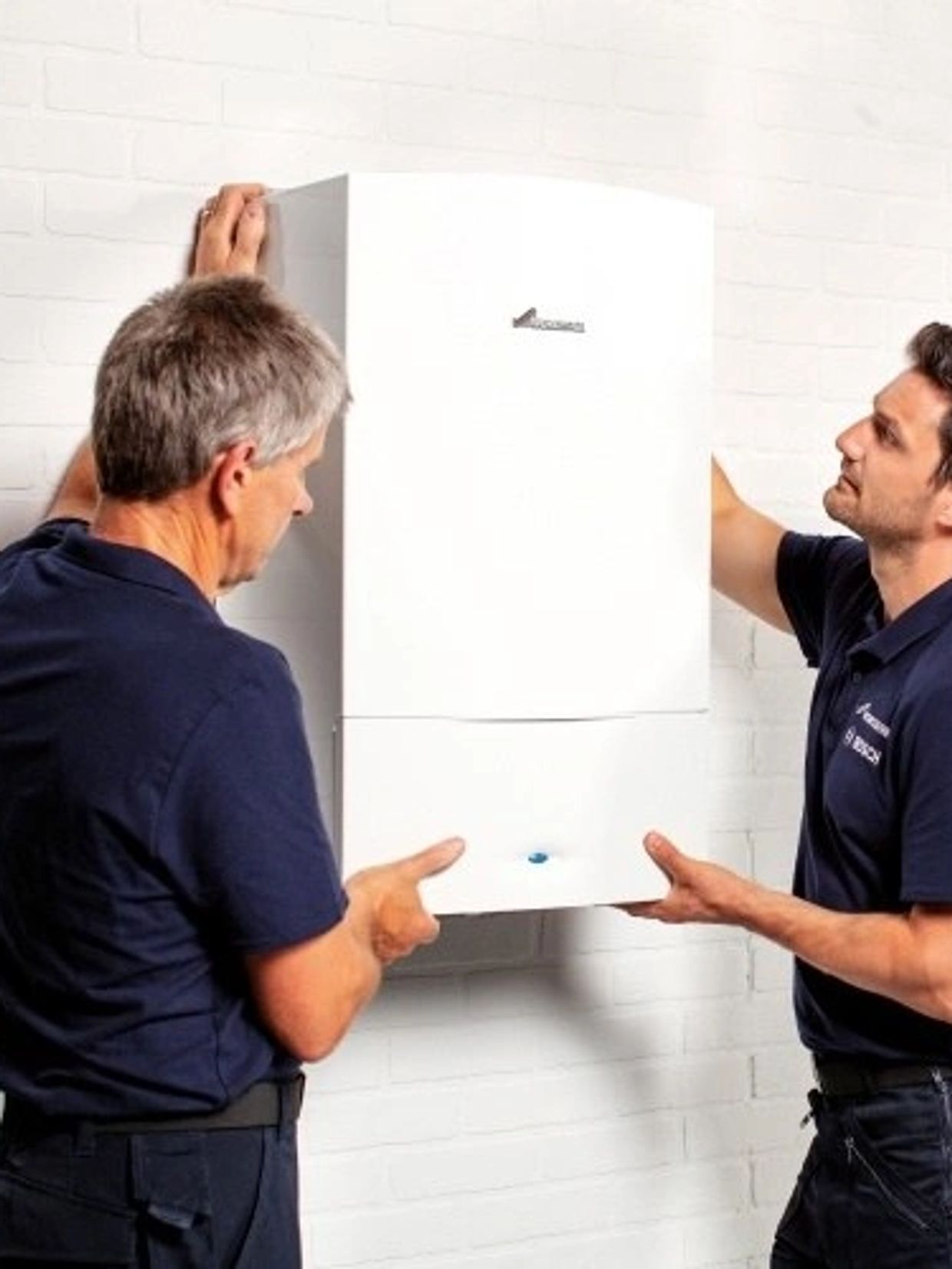 Two technicians installing a white appliance on a wall.