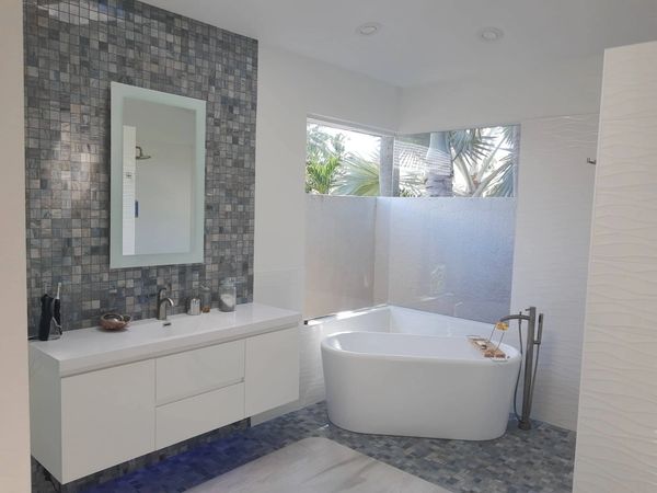 Modern bathroom with freestanding tub and mosaic tile wall.