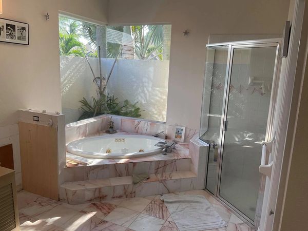 Bright bathroom with a corner whirlpool tub and glass shower enclosure.
