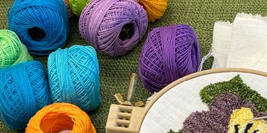 Colorful balls of yarn and a punch needle flower.