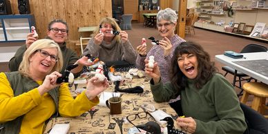 Smiling people holding up their felted art projects. 
