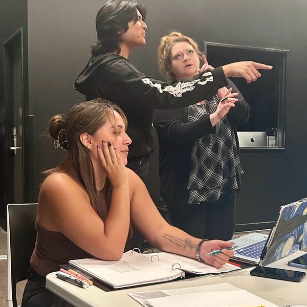 Three people collaborating in a creative workspace with focused expressions.