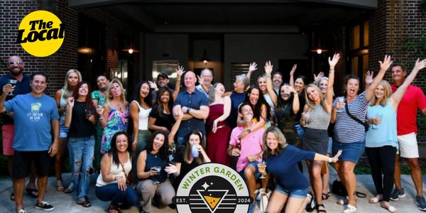 A lively group of people enjoying the Winter Garden Social event with drinks and smiles.