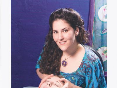 woman receiving facial massage from smiling massage therapist