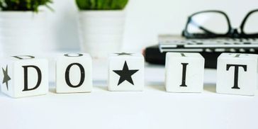 Blocks spelling out 'DO IT' with a star in between on a desk.