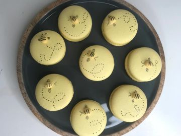 Yellow bee-themed macarons on a black plate.