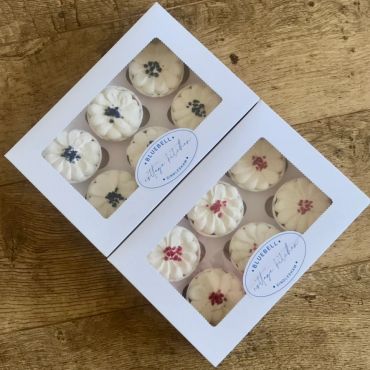Two boxes of flower-shaped cupcakes with different colored toppings.