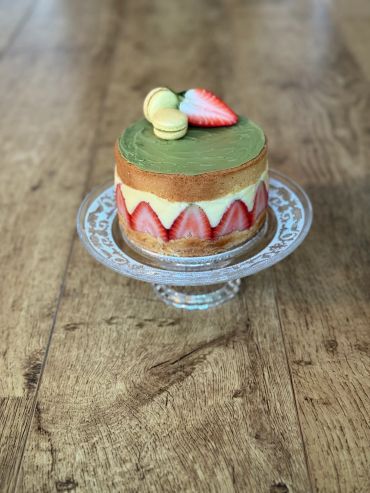 Elegant strawberry and matcha cake with macarons on top.