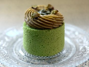 Green pistachio mousse cake with chocolate frosting and pistachios.
