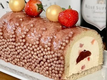 Strawberry roll cake with golden and red decorations.