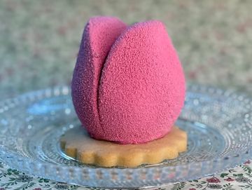 Pink velvet cake resembling a tulip on a cookie base.