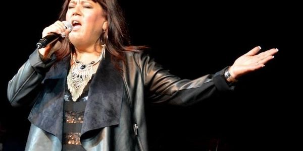 Female singer passionately performing on stage with a microphone.