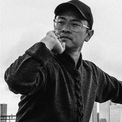 Man practicing martial arts outdoors with serious expression.