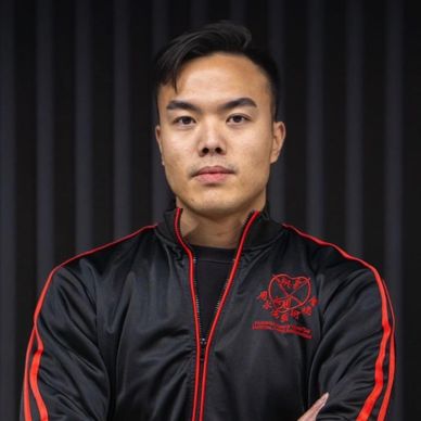 Young man in black and red jacket looking serious.
