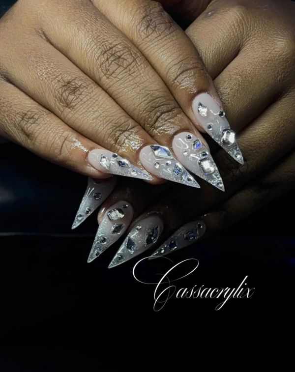 Long stiletto nails with silver and clear rhinestone embellishments.
