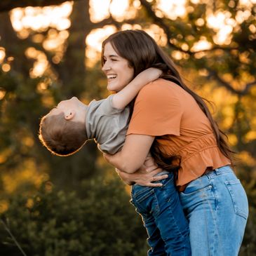Woman happily hugging a child outdoors.