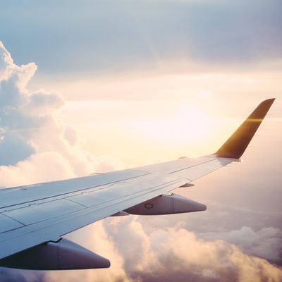 View of an airplane wing with the sun shining through clouds.