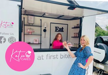 A woman serves cake from a white food truck.