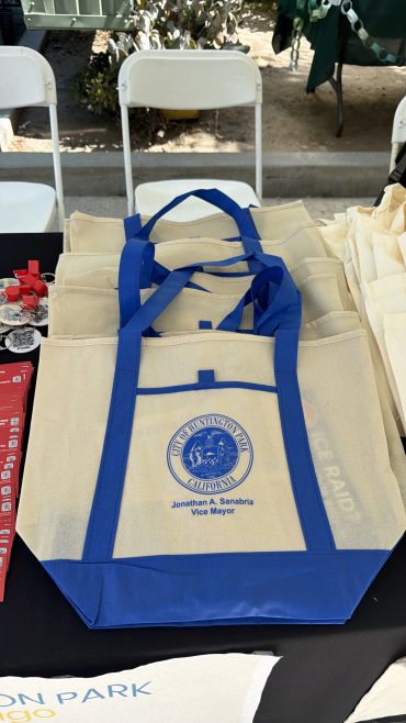 Reusable tote bags with blue handles and a city seal on a table.