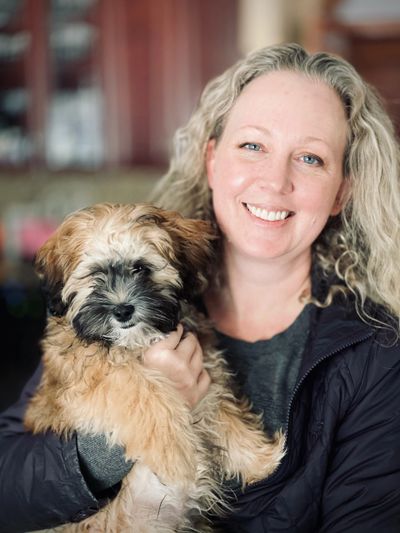 Smiling woman holding a fluffy puppy indoors.