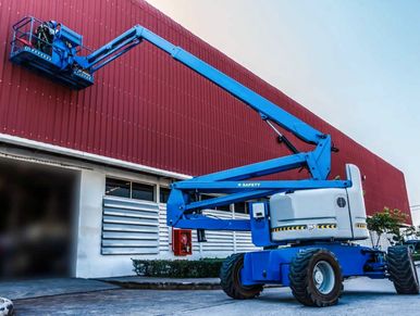 Blue boom lift reaching the top of a red building.