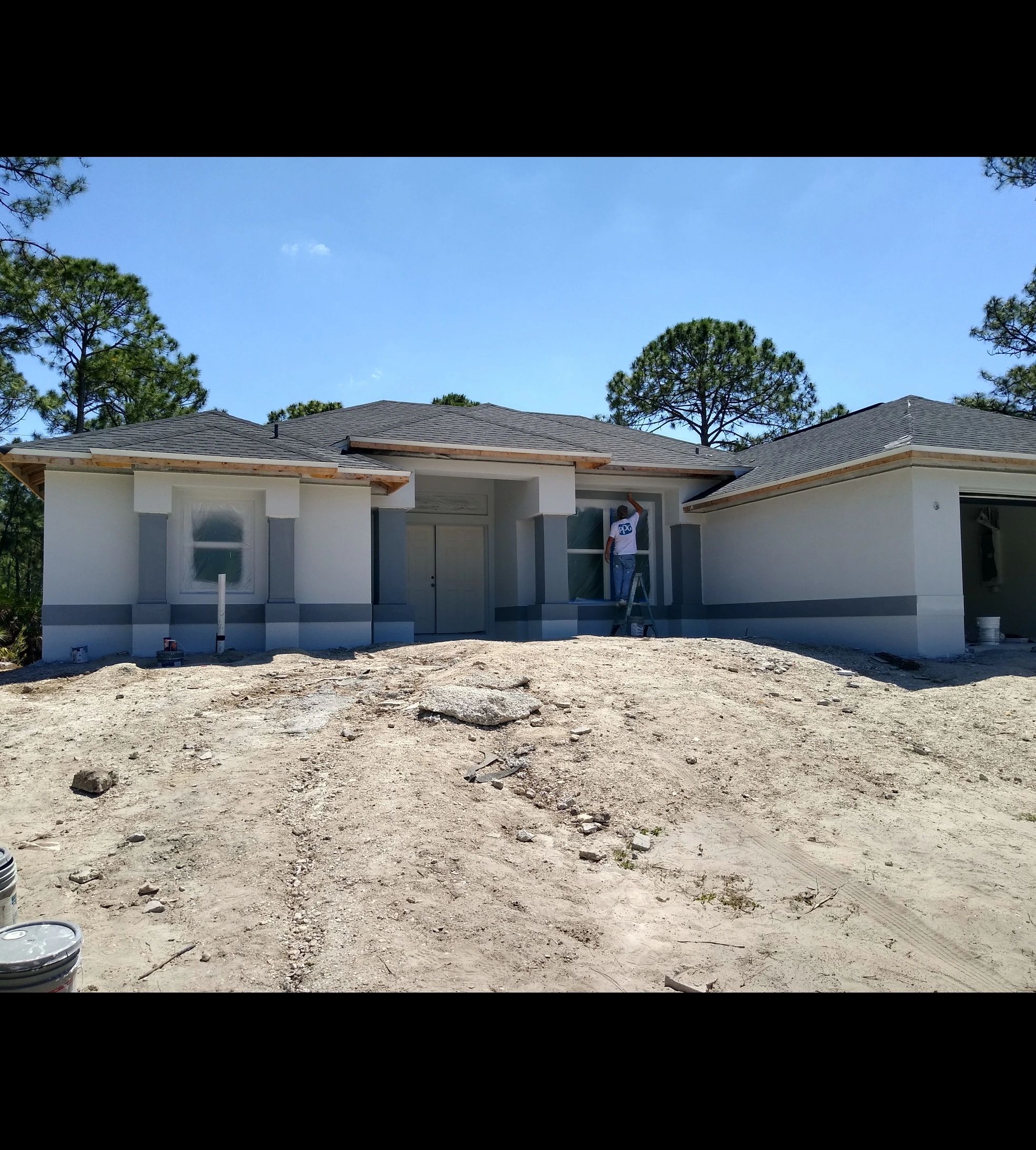 Painter working on a new construction home exterior in Venice, FL