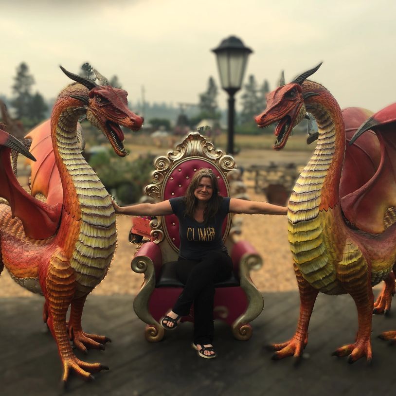 Woman sitting on a throne between two dragon statues.