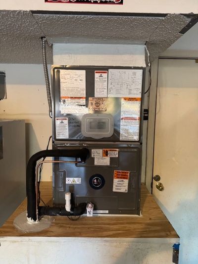 A modern HVAC unit installed in a home utility room with labels and pipes.
