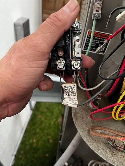 Hand holding electrical component near wiring.