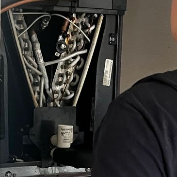Close-up of an HVAC coil inside a unit with a person partially visible.