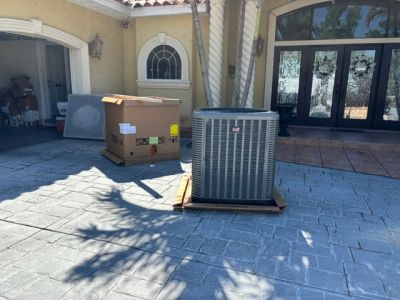 New air conditioning unit and its packaging box outside a house.