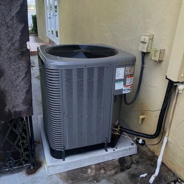 Modern outdoor air conditioning unit installed on a concrete pad beside a house.