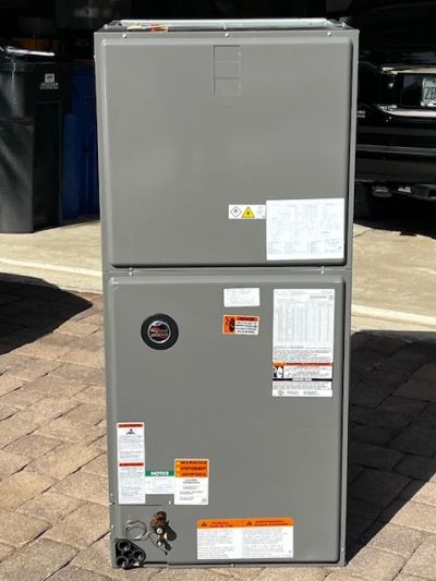 Gray HVAC unit with multiple warning and instruction labels outdoors.