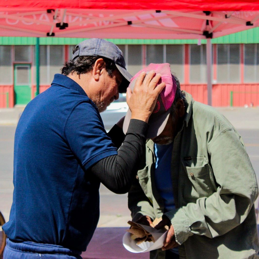 A man praying for and giving food to a homeless man on the street