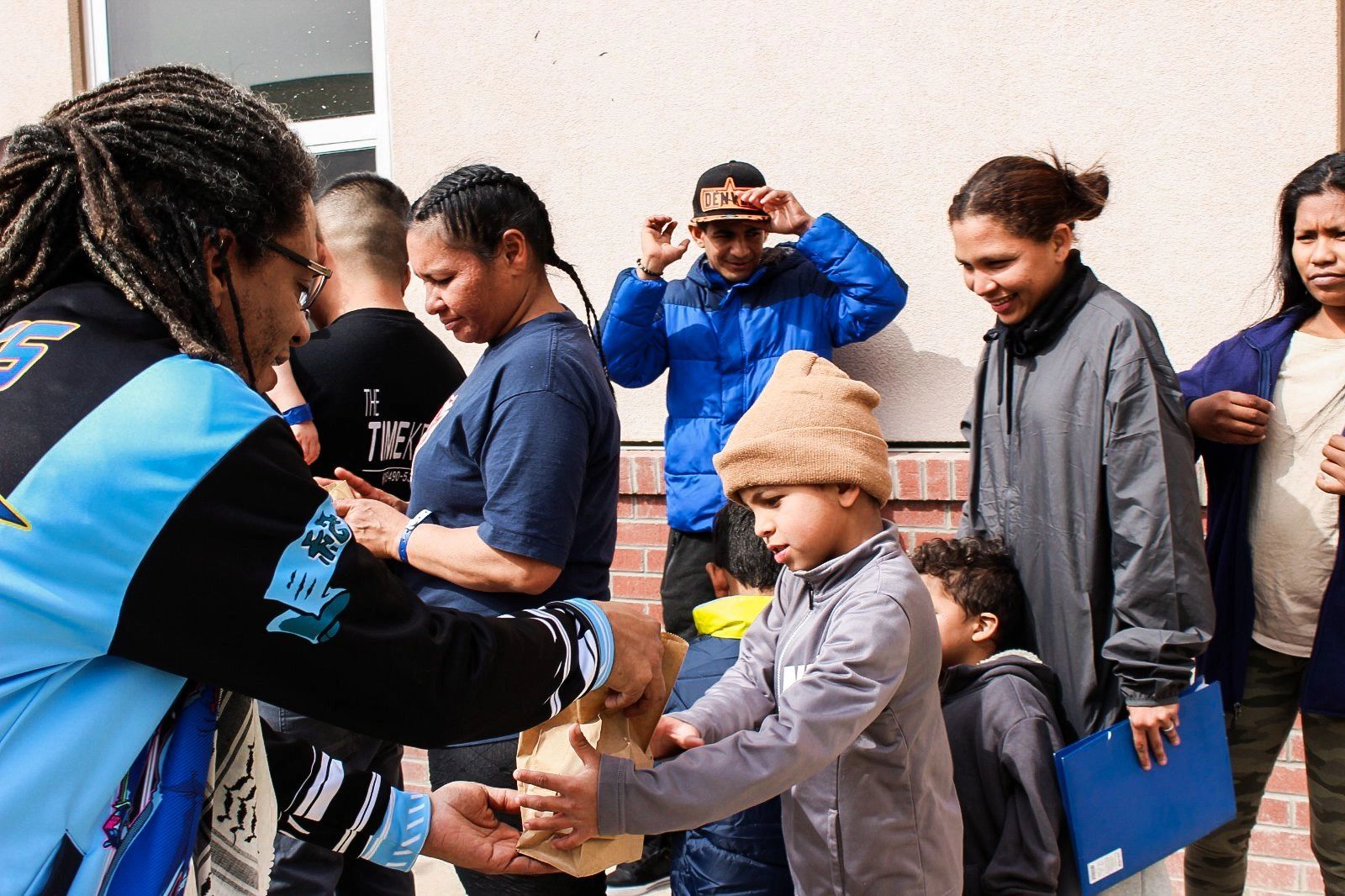 A woman giving food to a line of migrants