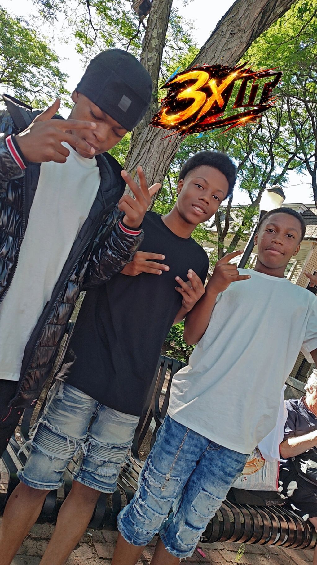 Three young men posing outdoors with hand signs and casual clothing.